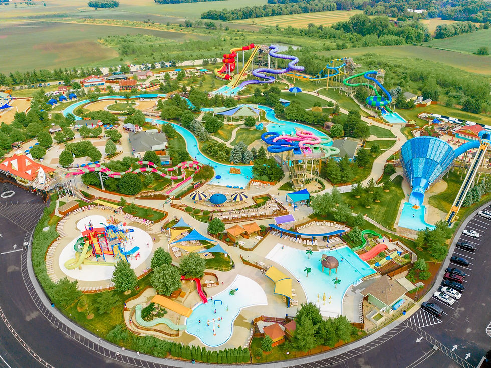 Arial photo of Raging Waves water park featuring lots of colorful water slides, water playground, a zero depth entry wave pool, twisting, long, and drop water slides, lazy river, lounge chairs, and more.