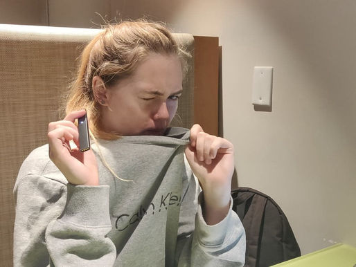 Girl blowing Juul smoke into sweatshirt worried she's "too addicted to her work"