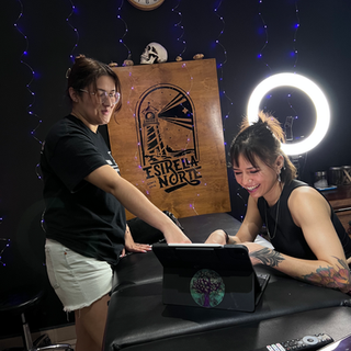 Mujeres viendo galeria de tatuajes en tablet en estudio.