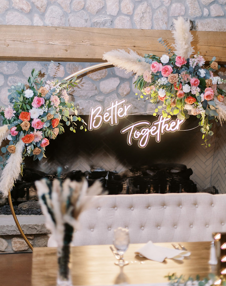 Floral sweetheart table design with Better Together neon sign and stone fireplace backdrop