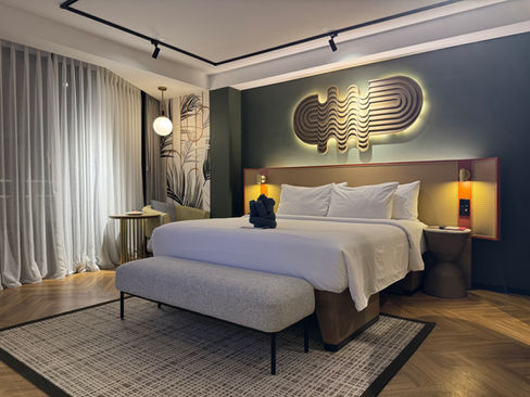 King bed in TRIBE Comfort XL room at TRIBE Bali Kuta Beach with seating area and full-height curtains