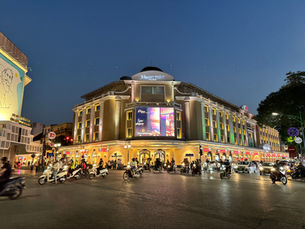 Evening view of Trang Tiền Plaza in Hanoi with motorbikes passing by, captured during a 4-day Vietnam travel itinerary