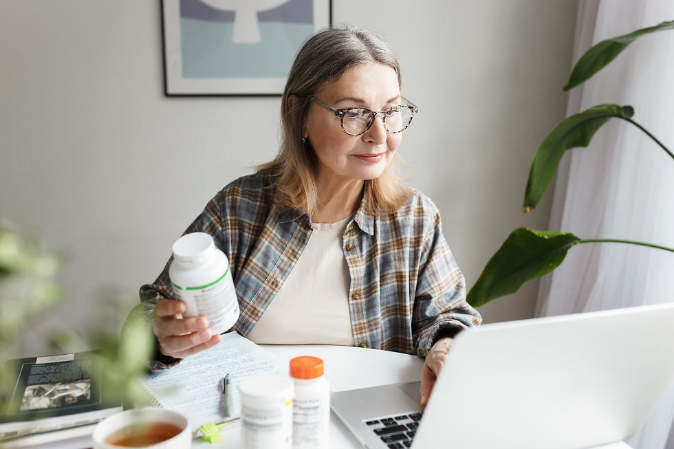 Porträt von gealterten Ernährungsberater Nahrungsergänzungsmittel auf dem Markt mit Laptop bestellen, hält Flasche Vitamine in der Hand, aufmerksam überprüfen Informationen Blick auf den Bildschirm