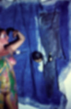 A woman in body paint in front of a draped canvas - colour photo