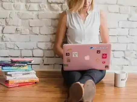 Mulher sentada no chão com notebook no colo, ilustrando o debate sobre o comportamento atual delas no artigo Mulheres traem melhor do que os homens.