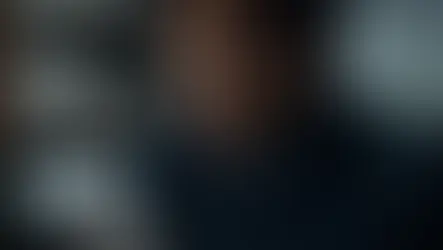 Homem de terno concentrado analisando mensagens em um smartphone em uma sala de monitoramento com arquivos ao fundo, ilustrando a atuação de um detetive hacker especialista em segurança digital.