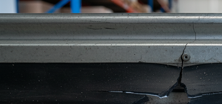 Close-up view of a damaged door seal at the base of a warehouse roller door.