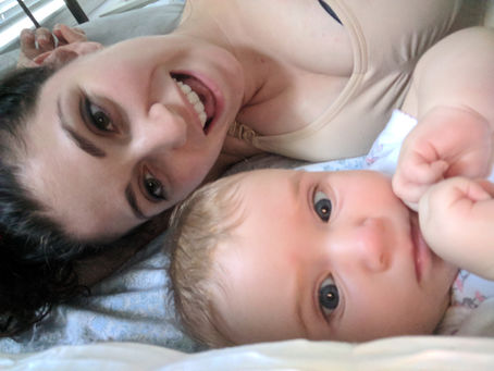 A mother and baby both smiling and looking at the camera taking a selfie
