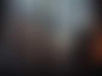 Woman standing by a window looking out at blooming spring blossoms under a dark, stormy sky, symbolizing reflection, uncertainty, and new beginnings during divorce mediation.