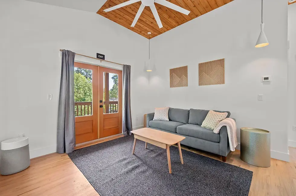 Modern living room in St Augustine Florida beach house rental with gray sofa, wooden beams, and balcony access