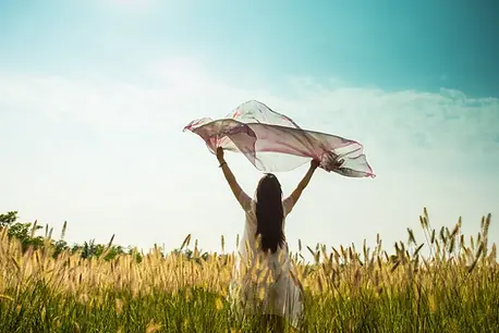 Woman holding a scarf in the air, symbolizing the freedom and empowerment that comes from reconnecting with her inner child.
