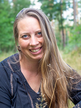 Eine Frau mit langen Haaren, die Fotografin von Tuulafotografie, schaut lächelnd in die Kamera