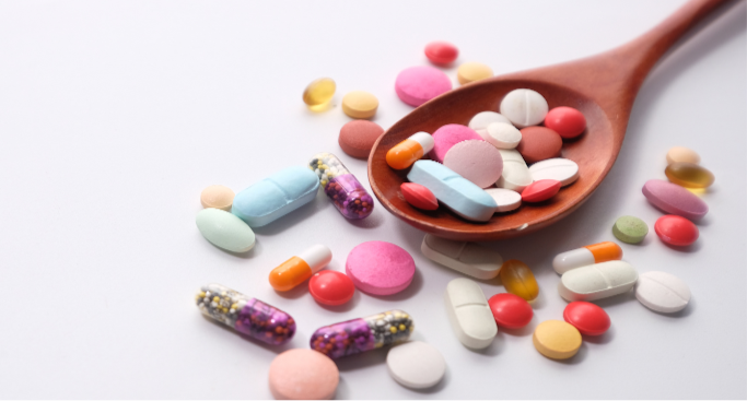 A spoon with various pills laying out on a flat surface. This represents different types of medications that may be needed for psychiatric use in katy, texas.