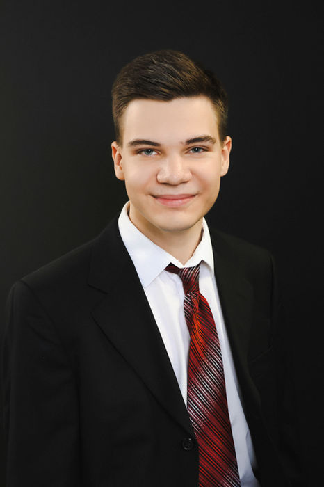 Formal corporate headshot of a man wearing a suit and tie, photographed against a dark studio background. Ideal for executive profiles, legal or finance professionals, and high-level business branding.