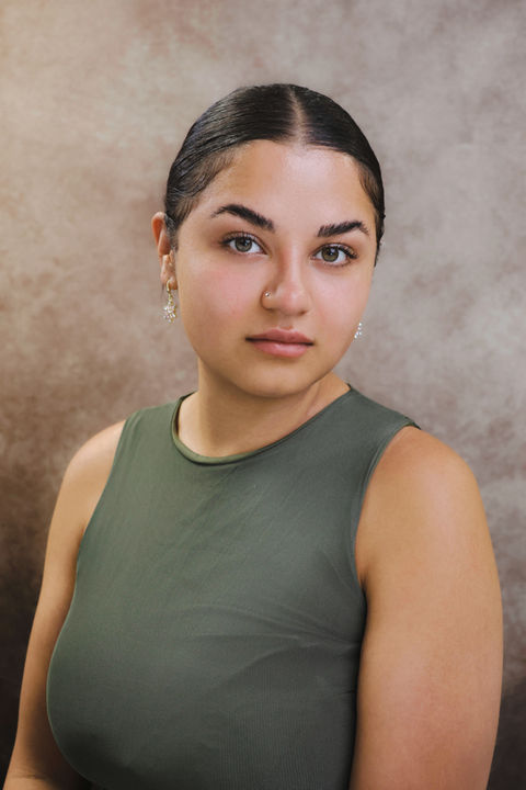 A natural portrait of a woman wearing a sleeveless green top, photographed against a neutral backdrop at a King’s Cross portrait studio, ideal for artists, founders, or personal website use.