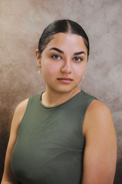 A natural portrait of a woman wearing a sleeveless green top, photographed against a neutral backdrop at a King’s Cross portrait studio, ideal for artists, founders, or personal website use.