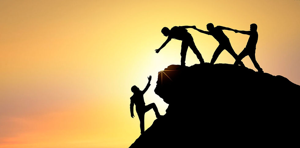 Three people form a chain to help a fourth person up a mountain