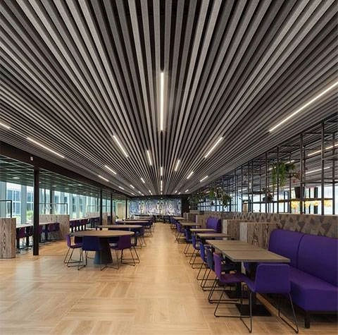 Spacious modern dining hall featuring striped ceiling and purple benches.