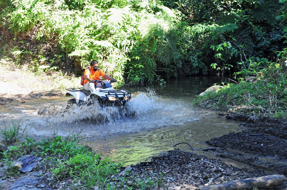 A man drives an ATV through a river in Belize