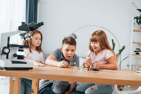 Three homeschool children explore a chemistry model