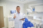 A smiling dentist gives a thumbs up.