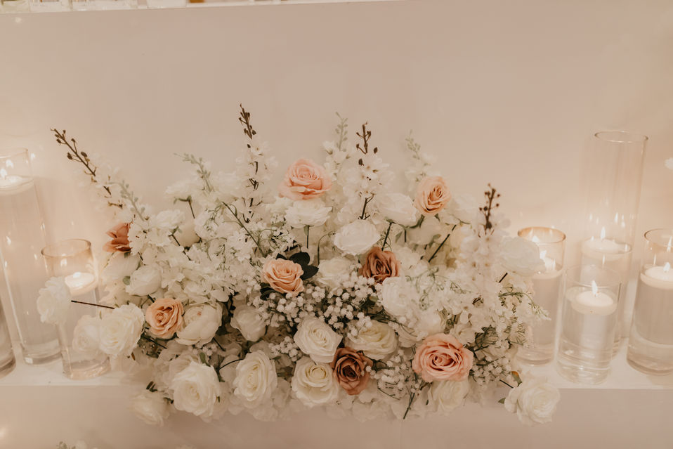 Soft pink and cream floral centerpiece for an elegant wedding dinner setup in Alberta.