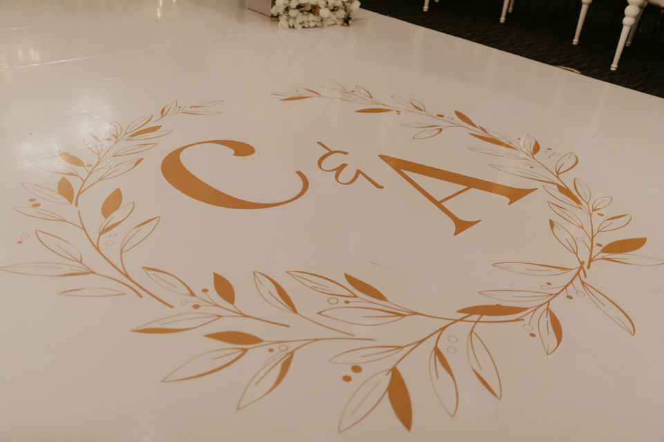 White and gold wedding dance floor featuring custom initials for a modern luxury reception.