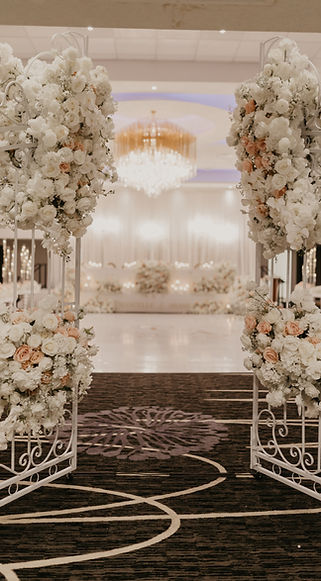 Ornate gates opening into an elegant wedding reception, framed with white and blush floral arrangements at the Wyndham Edmonton Hotel and Conference Centre