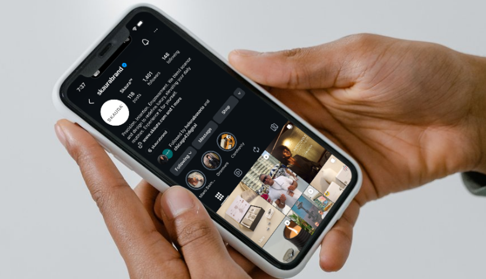 Person holding a smartphone scrolling through SKAURA  social media profile.