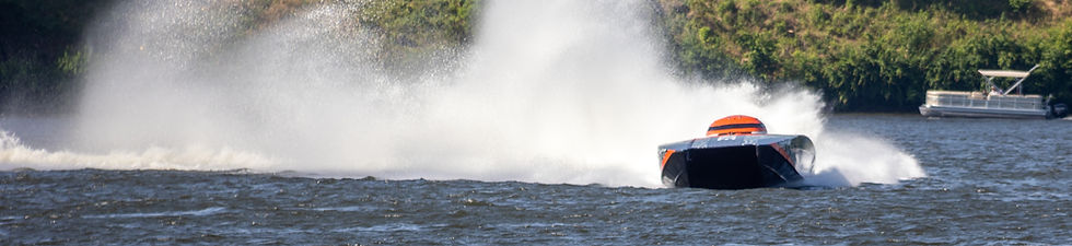 Powerboat racing with white water spray trail.