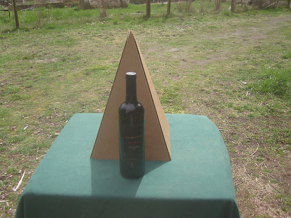 Fold-up Nubian Cardboard Pyramid with a bottle of wine in front for comparison.