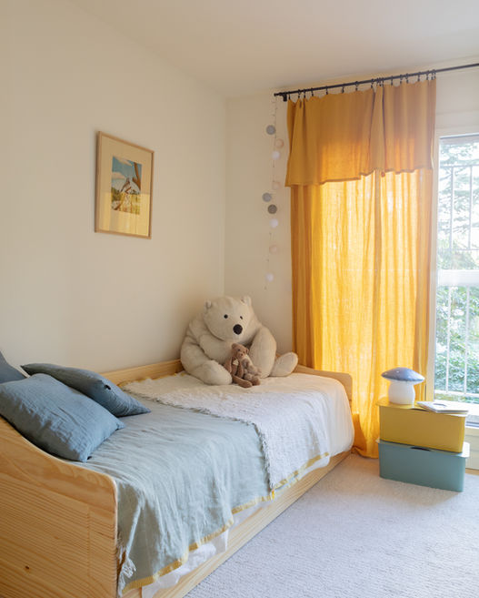 Chambre d’enfant avec lit en bois clair et rideaux jaunes – Projet Valmy à Paris.
