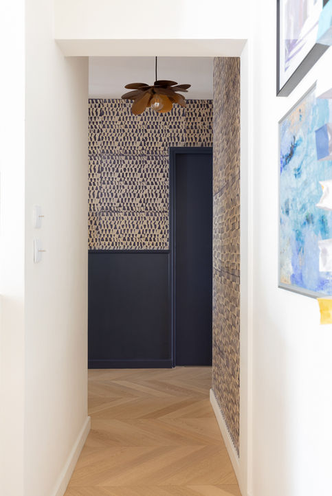 Couloir rénové avec papier peint graphique bleu et suspension fleur poétique.