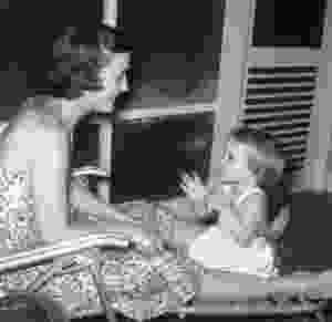 mother and daughter sitting on chair on porch