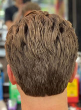 Back view of a men’s medium-length scissor haircut with layered texture and natural flow through the crown and neckline.