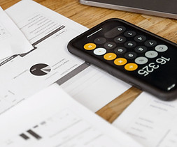 A desktop setup with accounting papers and a calculator on a smartphone.
