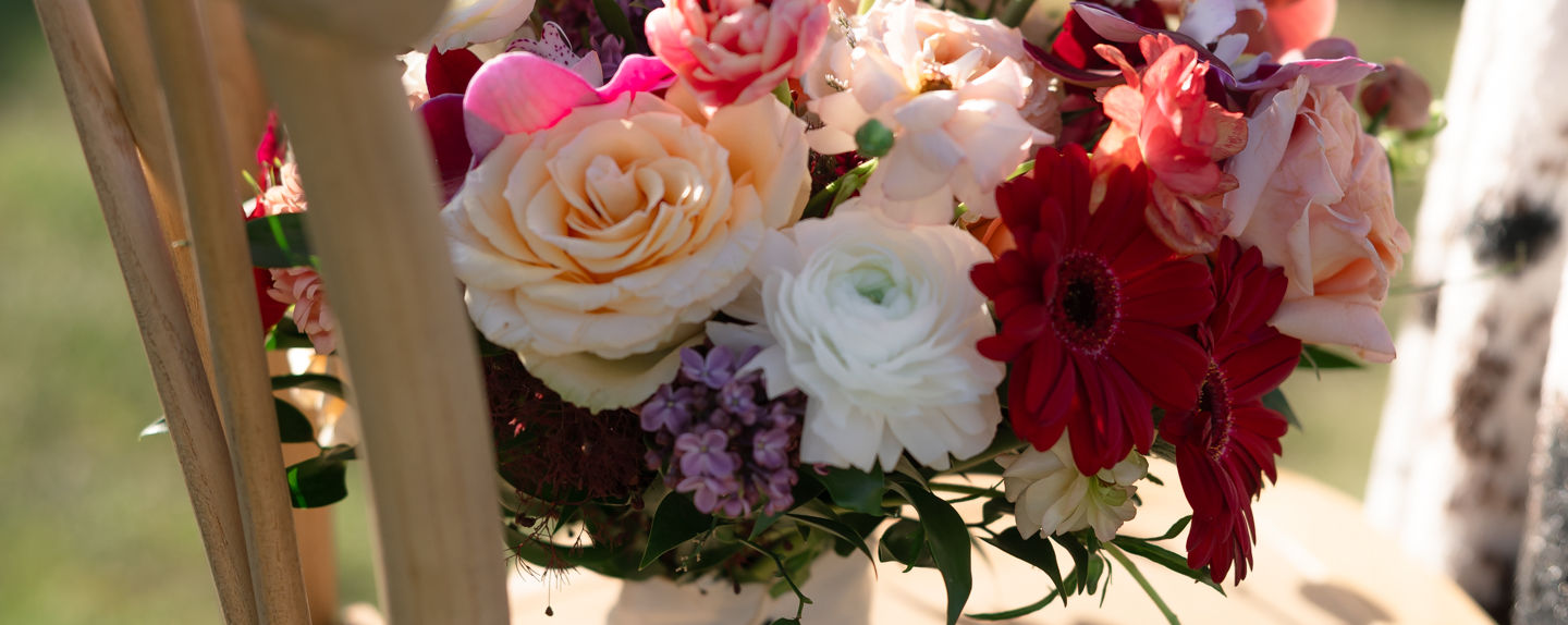 bouquet of flowers rests on a wooden chair in the gardens