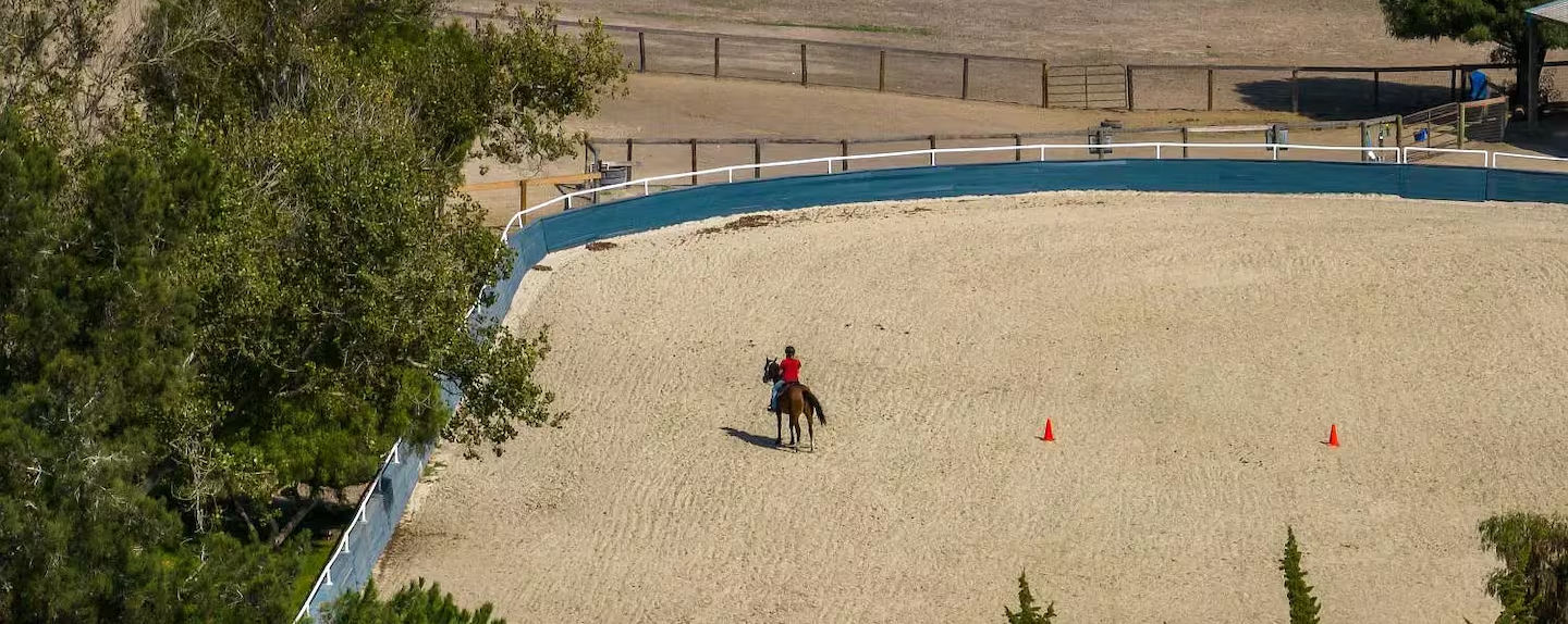 person rides a horse through the pasture at our wedding venue