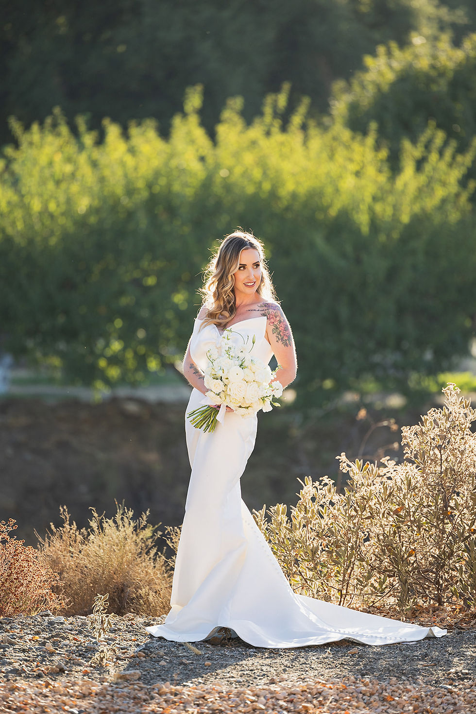 An elegant bride taking pictures outside the wedding venue in a desert-like landscape