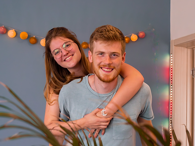 Coach lara omhelt coach martijn via zijn rug en lachen samen naar de camera