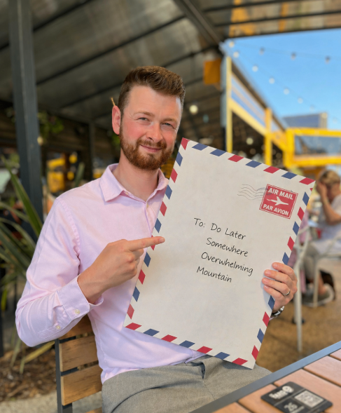 ADHD Coach Michael Ling in Cambridge cafe holding an oversized envelope