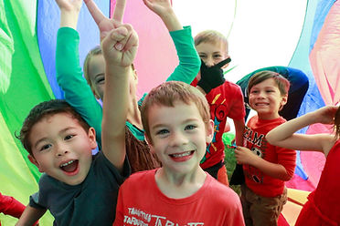 Kids under parachute at after school care program Rhema Christian School