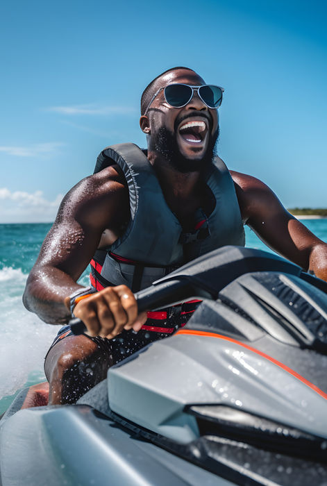 Un homme antillais fait du jetski et s'amuse, il sourit à pleines dents.