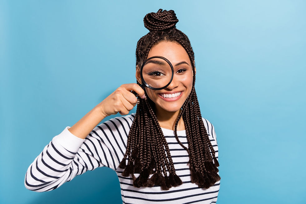 Smiling woman holding a magnifying glass in front of her eye, symbolizing the importance of screening and