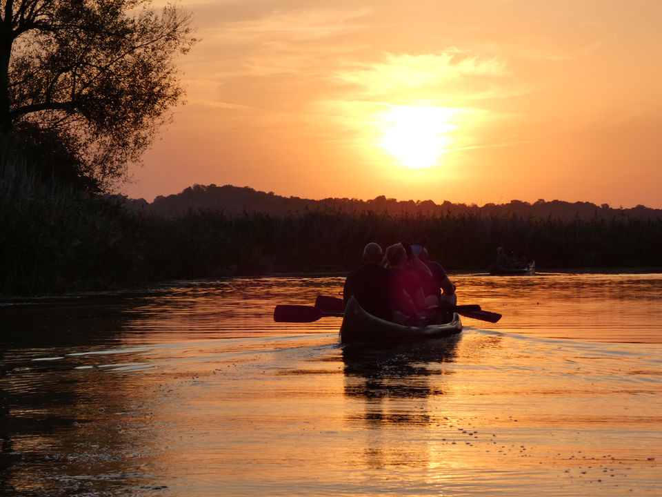 Personen in einem Kanu auf einem See bei Sonnenuntergang