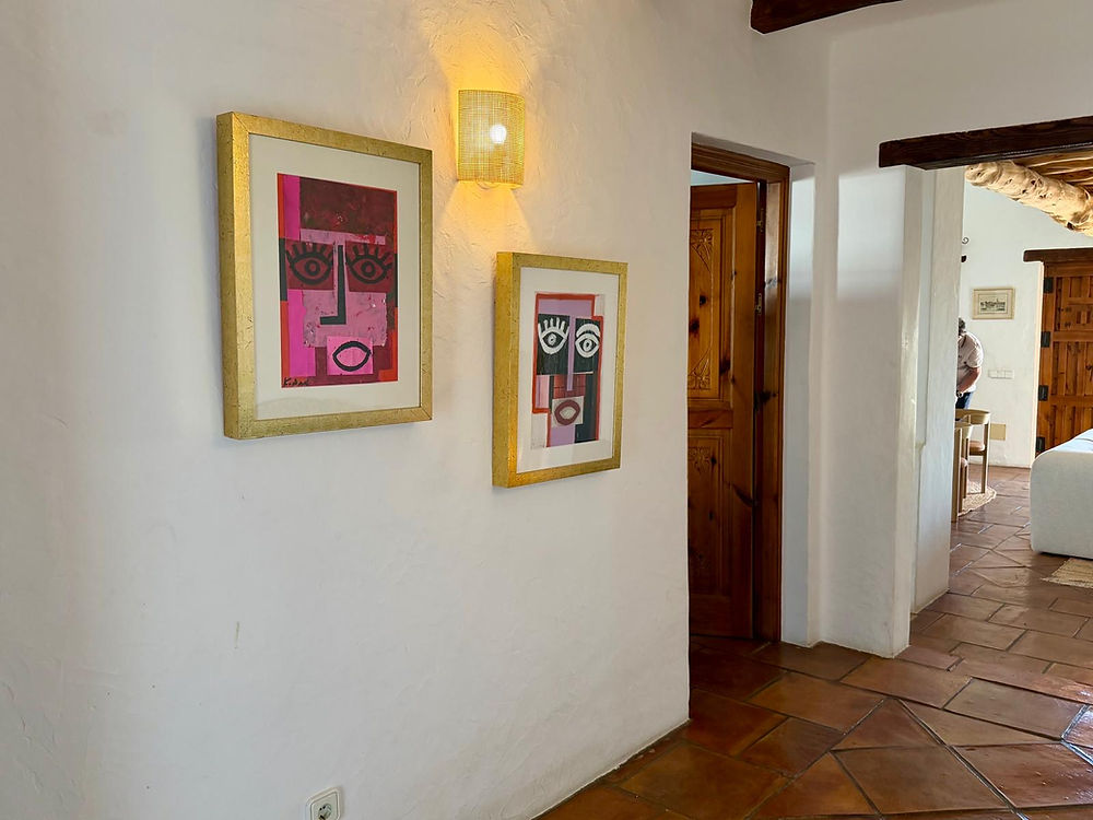 Hallway with two framed artworks, sconce light, tiled floor