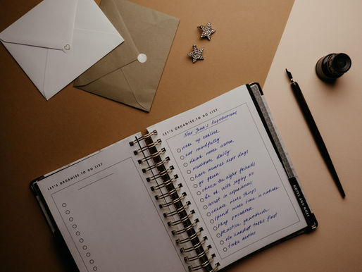 Open planner with a fountain pen and envelopes on a pale desk