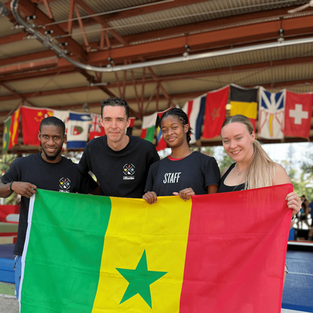 Groupe de campeurs internationaux tenant un drapeau du Sénégal