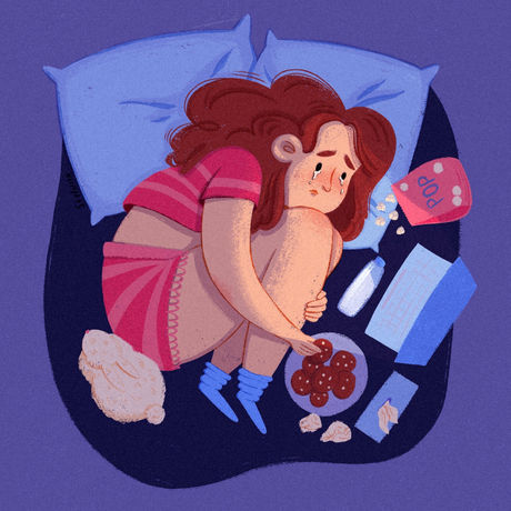 An illustration of a girl curled up in bed watching something on her laptop, surrounded by snacks like popcorn and cookies. She looks sad but comfortable.