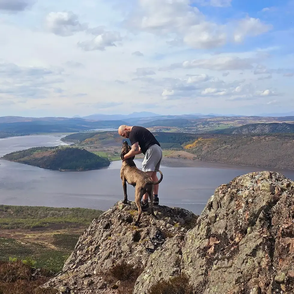 Hairy Highlander on a mountain stroking a dog